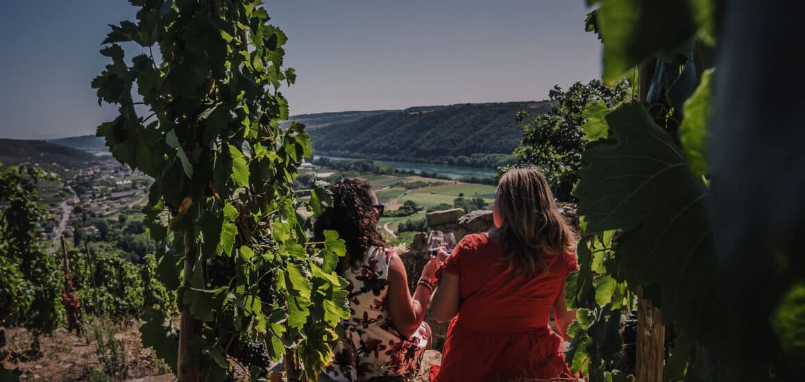 Deux femmes trinquant avec un verre de vin devant le Rhône