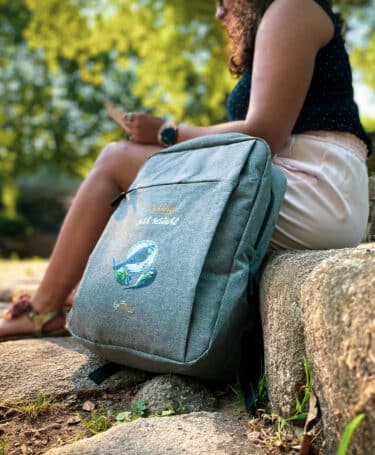 Jeune femme assise avec un sac à dos de la gamme Epicurieux de tout