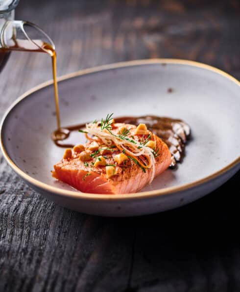 Assiette garnie avec du poisson et un jus versé dans le plat